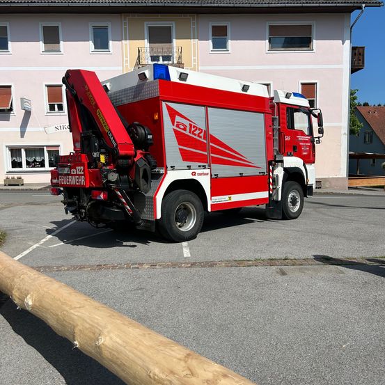 Ein rot-weißer Feuerwehrwagen mit der Nummer 122 ist vor einem rosa Gebäude geparkt.