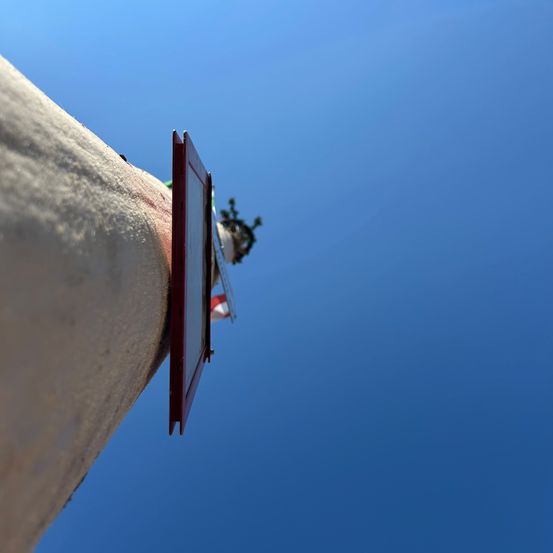 Ein Nahaufnahme einer hohen Gebäudes mit blauem Himmel und einer Fahne an der Seite