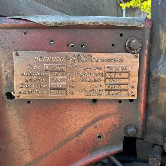 Ein Nahaufnahme einer Metallplatte mit Heinrich Lanz Mannheim Details, einschließlich Typ D 7506, Motorleistung 7274 cm3, 850 U/min, 25 PS und Produktionsjahr 1944. Gewichtsdetails umfassen 2650 kg leer, 3400 kg Gesamt, 1400 kg vorne und 2000 kg hinten.