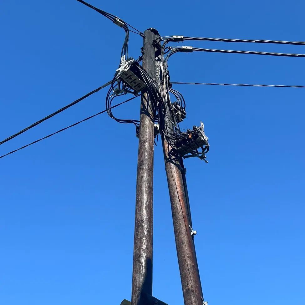 Ein Versorgungsmast mit mehreren Drähten und elektrischen Geräten.