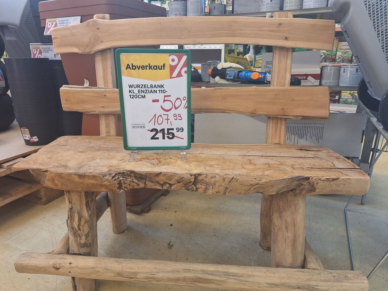 A wooden bench with a sign indicating a sale of 50% off, showing the original price of 107.99 and the discounted price of 215.99.