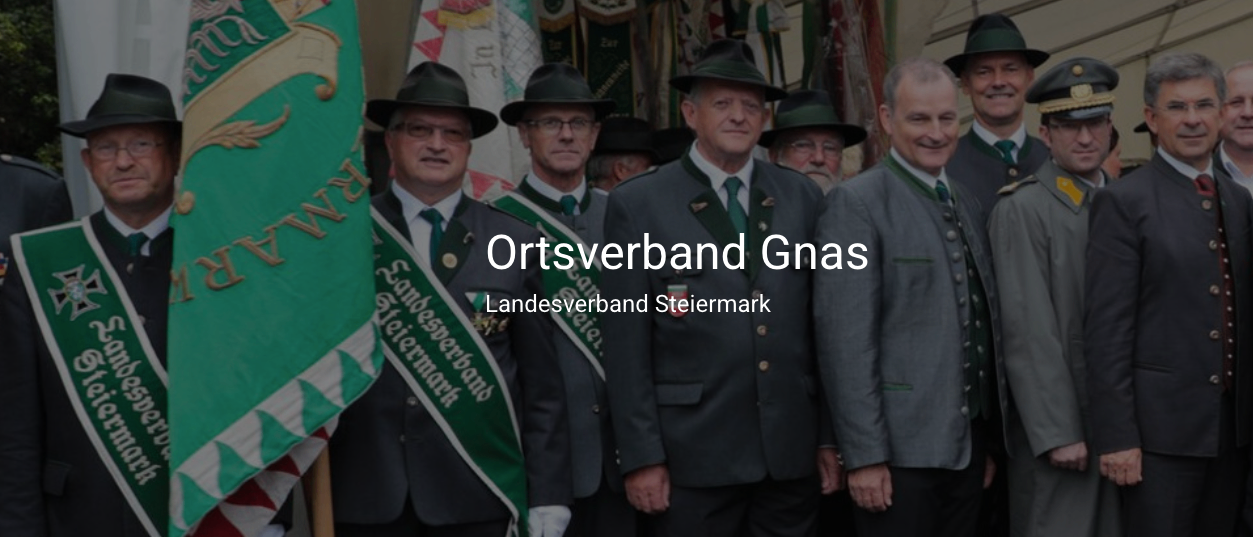 Gruppe von Männern in Uniformen mit Hüten, die für ein Foto zusammenstehen, 'Gnas' Text unten sichtbar.