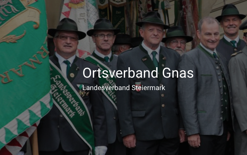 Gruppe von Männern in Uniformen mit Hüten, die für ein Foto zusammenstehen, 'Gnas' Text unten sichtbar.