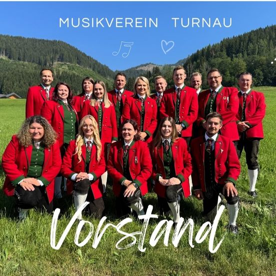 Eine Gruppe von Menschen in traditioneller roter und grüner Kleidung posiert für ein Foto auf einer Wiese mit Bergen im Hintergrund. Der Text 'Vorstand' ist in Weiß unten geschrieben.