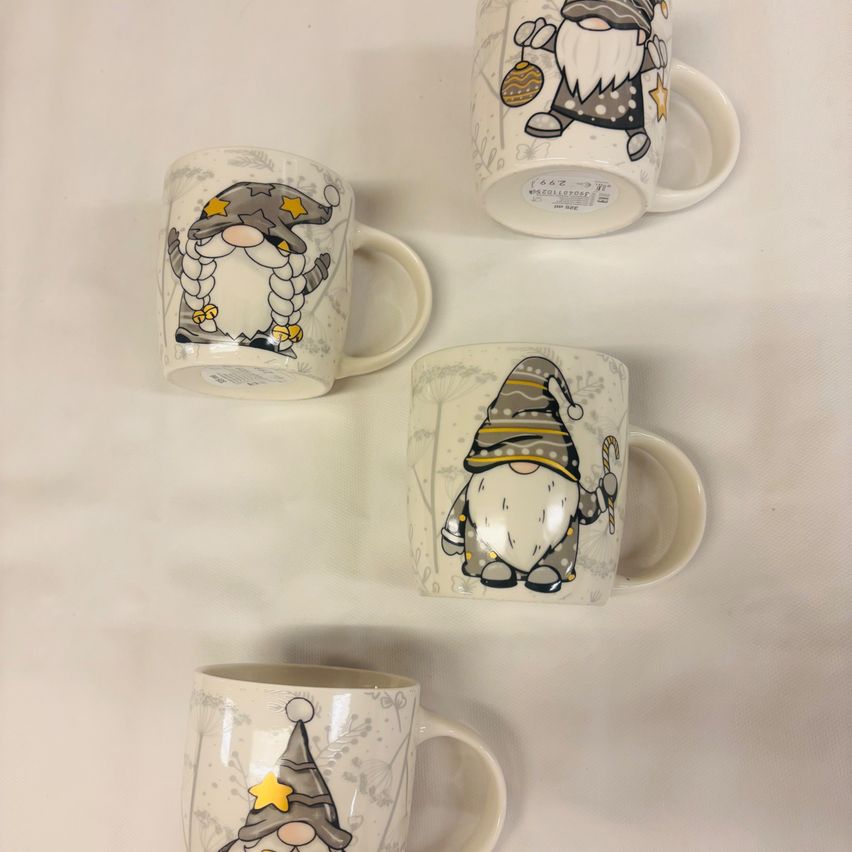 Vier Kaffeebecher mit Zwergendesigns darauf. Ein Zwerg hält ein Ei, ein anderer hat einen Stern, ein dritter hat eine Zuckerstange und der letzte trägt einen Hut.