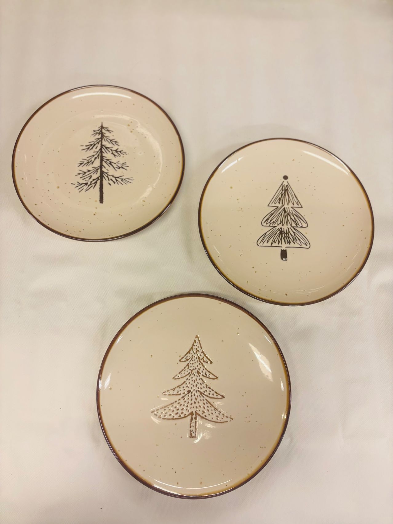 Drei Keramikteller mit braunen Baumdesigns auf weißem Hintergrund. Jeder Teller hat eine einzigartige Baumillustration.