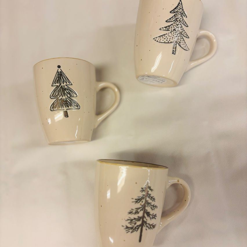 Drei cremefarbene Tassen mit Baumdesigns sind auf einer weißen Oberfläche ausgestellt. Jede Tasse zeigt eine andere Baumillustration.