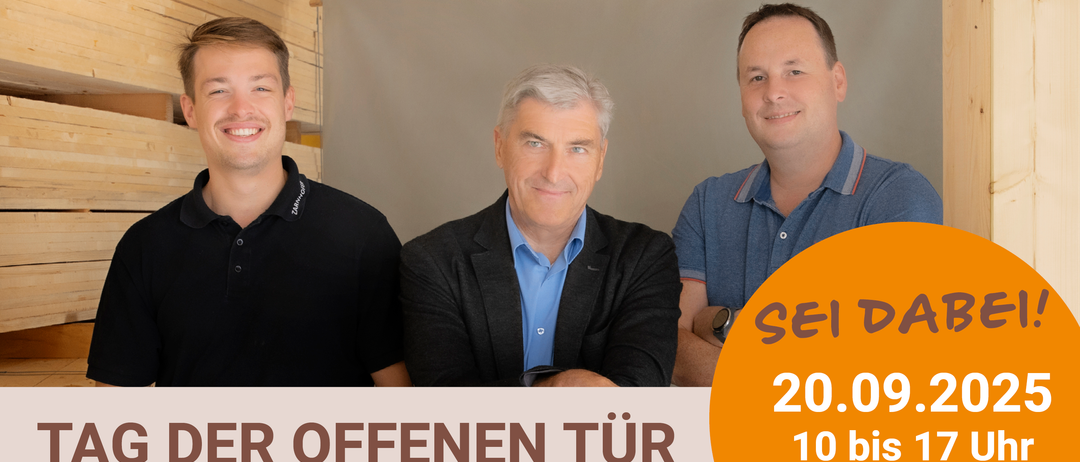 Drei Männer stehen in einem Raum mit einer grauen Wand im Hintergrund. Sie lächeln. Der Mann auf der linken Seite trägt ein schwarzes T-Shirt. Der Mann in der Mitte trägt ein blaues Hemd und eine schwarze Jacke. Der Mann auf der rechten Seite trägt ein blaues Poloshirt.