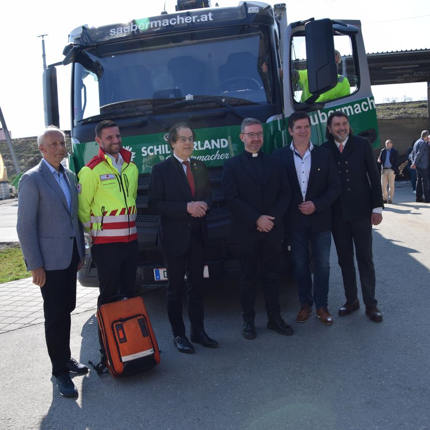 Fünf Männer stehen vor einem grün-weißen Lastwagen mit dem Namen Schiller-Land-macher. Der Mann auf der linken Seite hat einen orangefarbenen Rucksack.