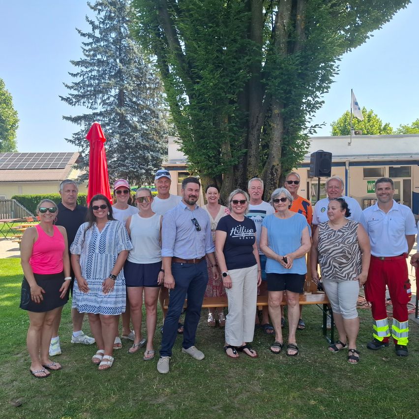 Eine Gruppe von Menschen posiert für ein Foto vor einem Baum in einem Park. Das Foto wurde tagsüber aufgenommen.