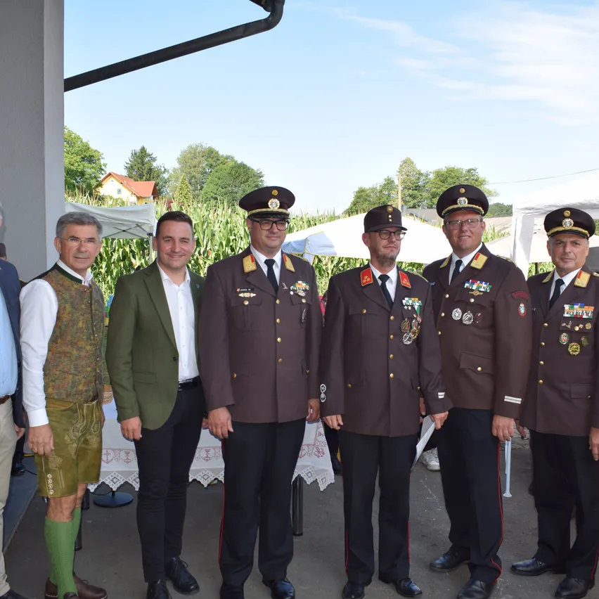 Eine Gruppe von Männern in Militäruniformen und Medaillen steht zusammen draußen. Hinter ihnen sind Zelte und Bäume.