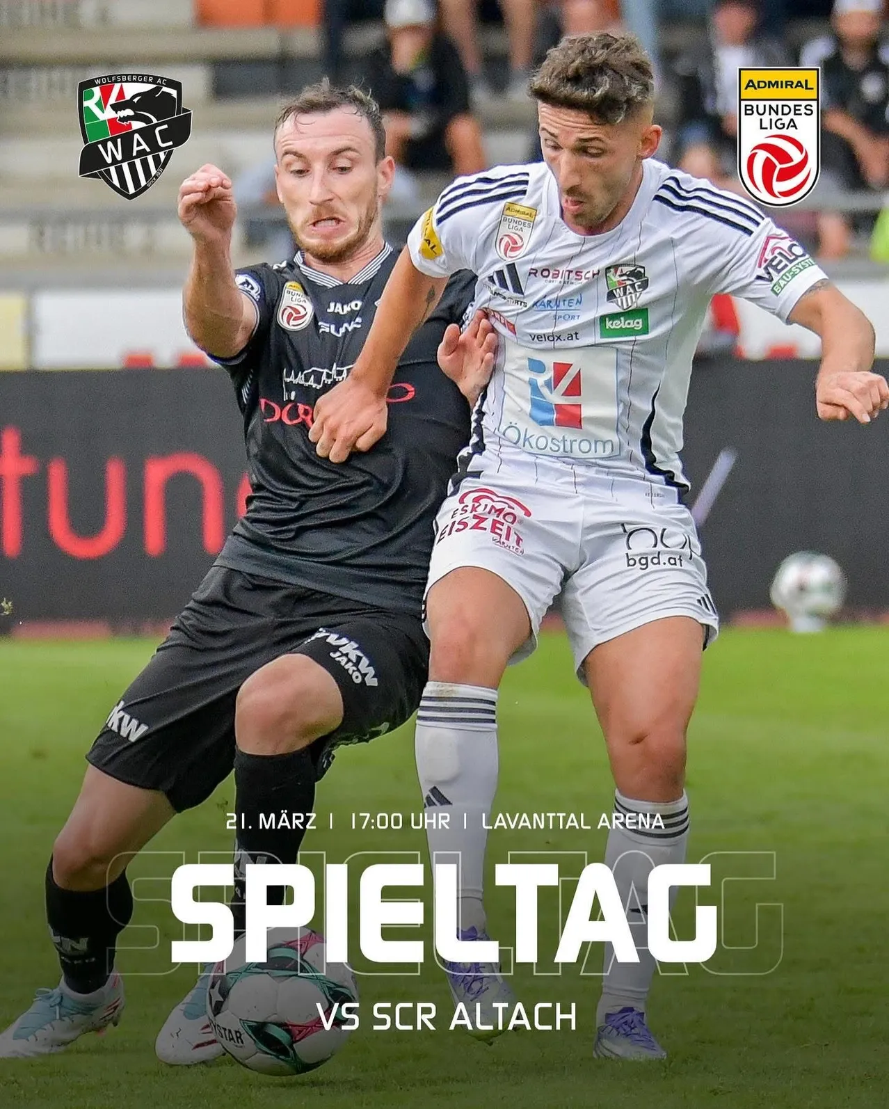 Zwei Fußballspieler konkurrieren auf einem Feld. Der Spieler in Schwarz verteidigt, während der in Weiß angreift. Das Spiel findet in der Lavantal Arena statt.