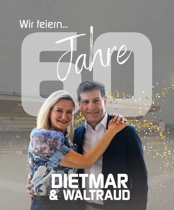 Ein Paar feiert sein 60-jähriges Jubiläum in einem Stadion. Der Mann und die Frau lächeln und umarmen sich. Im Hintergrund ist ein unscharfes Stadion und goldene Konfetti zu sehen.