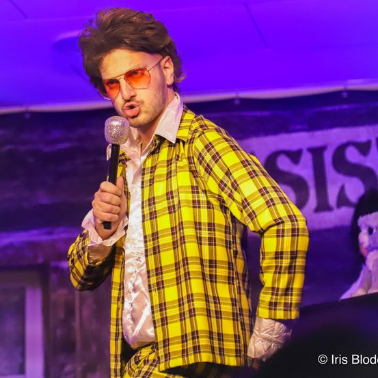 Bild enthält, Person, Solo Performance, Microphone, Adult, Male, Man, Stage, Crowd, Face, Glasses