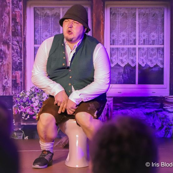 Bild enthält, Purple, Adult, Male, Man, Person, Sitting, Indoors, Stage, Face, Shoe