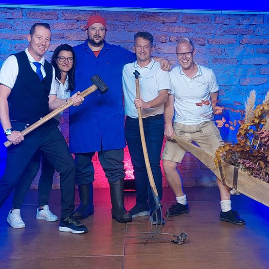 Bild enthält, Groupshot, Person, Adult, Male, Man, Group Performance, Axe, Wheel, Shoe, Face