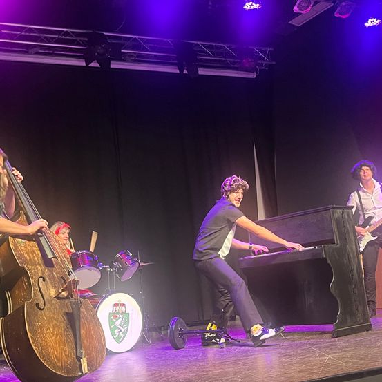 Bild enthält, Person, Guitar, Musical Instrument, Concert, Group Performance, Stage, Music, Musician, Performer, Shoe