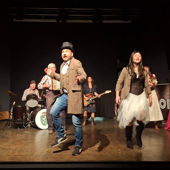 Bild enthält, Stage, Group Performance, Person, Adult, Male, Man, Guitar, Music Band, Shoe, Coat