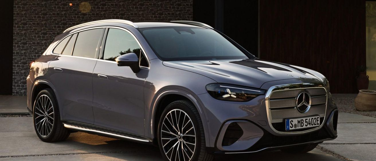 Ein schlanker grauer Mercedes-Benz SUV mit modernem Design steht vor einem Backsteingebäude.