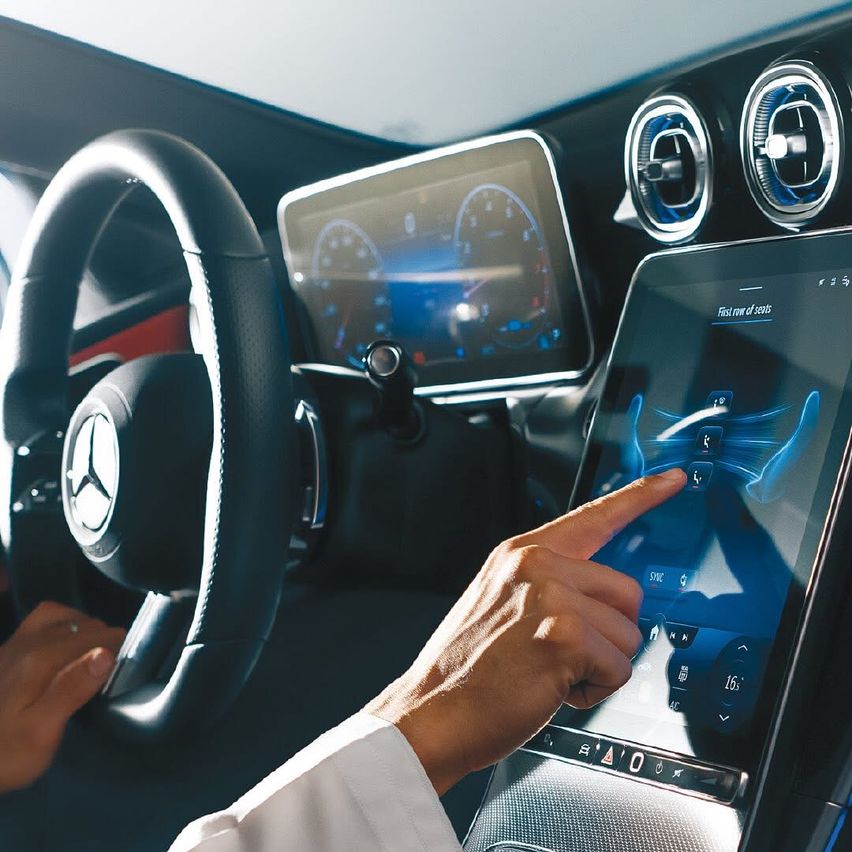 Hand zeigt auf Touchscreen im Auto, Armaturenbrett zeigt Geschwindigkeit und andere Metriken an.