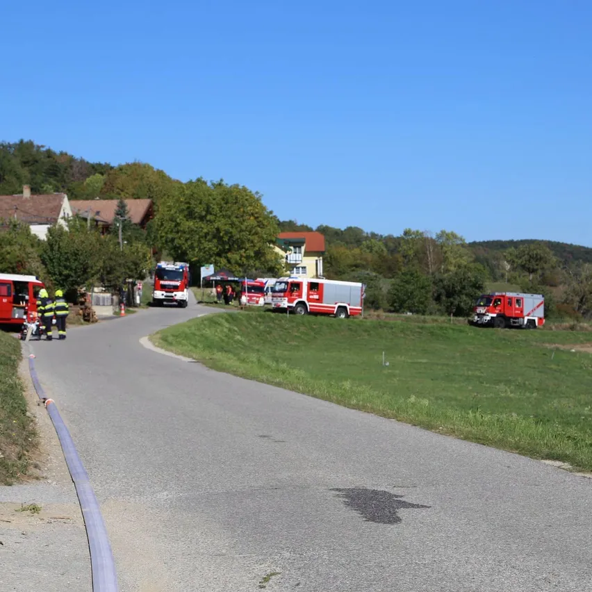 Ein Feuerwehrauto ist am Straßenrand geparkt, Feuerwehrleute in gelben Uniformen.