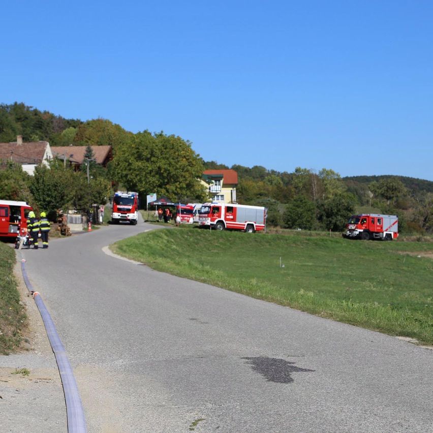 Ein Feuerwehrauto ist am Straßenrand geparkt, Feuerwehrleute in gelben Uniformen.