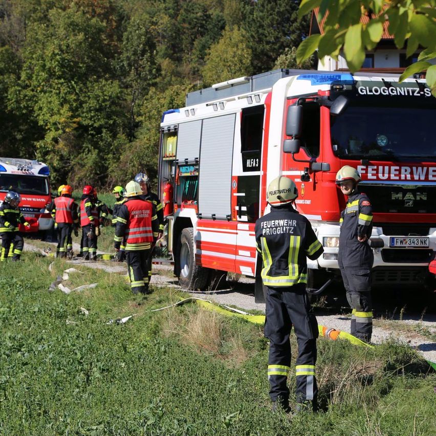 Eine Gruppe von Feuerwehrleuten steht auf einem Feld mit einem Feuerwehrwagen und einem Krankenwagen.