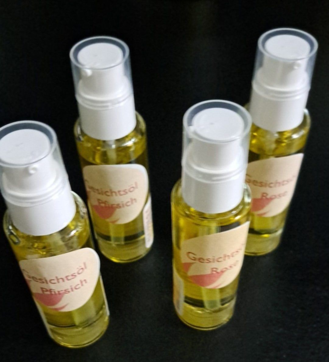 Fünf Flaschen Gesichtsöl Pfirsch, ein gelbes Gesichtsöl, auf einem schwarzen Hintergrund präsentiert.