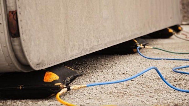 Eine Betonwand mit schwarzen aufblasbaren Beuteln darunter, verbunden durch blaue und grüne Kabel. Die Wand hat einen Metallteil an der Seite.