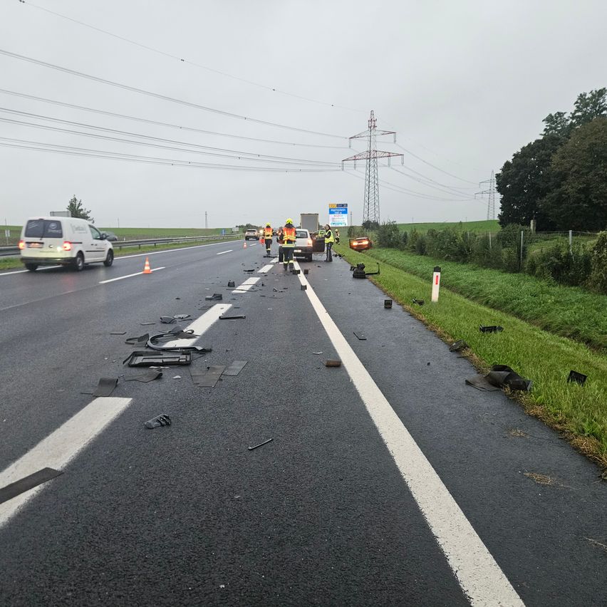 Ein Autobahnunfall mit verstreutem Trümmer, Einsatzkräfte in gelben Westen und Stromleitungen im Hintergrund.