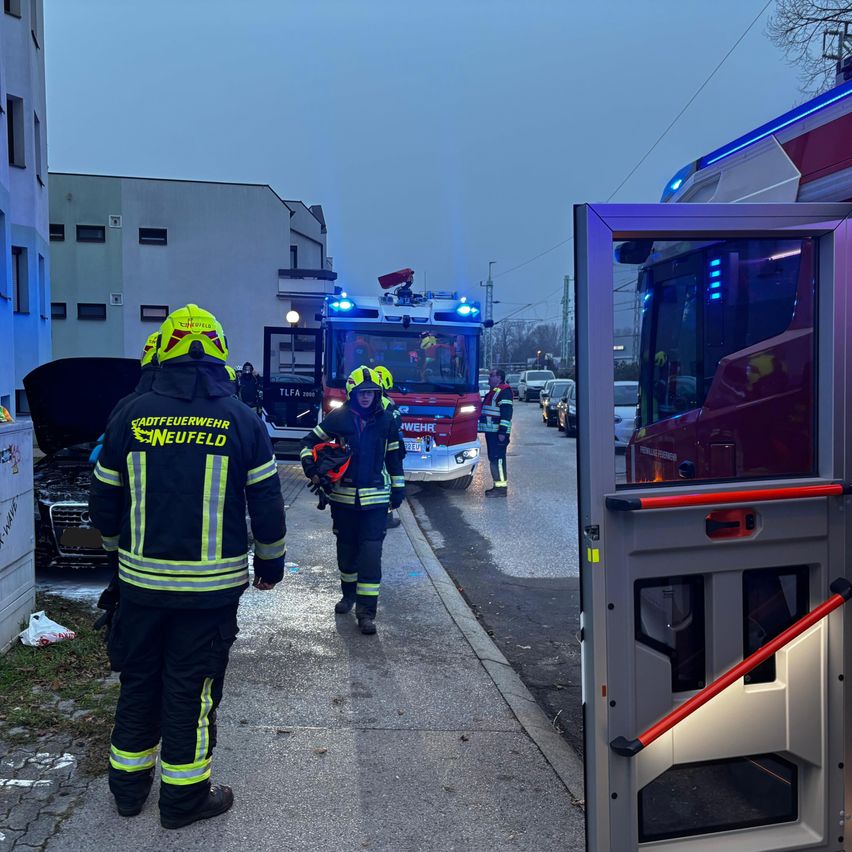 Feuerwehrleute aus Neufeld sind am Unfallort eines Autounfalls. Ein Auto ist beschädigt, und ein Feuerwehrauto ist in der Nähe geparkt.