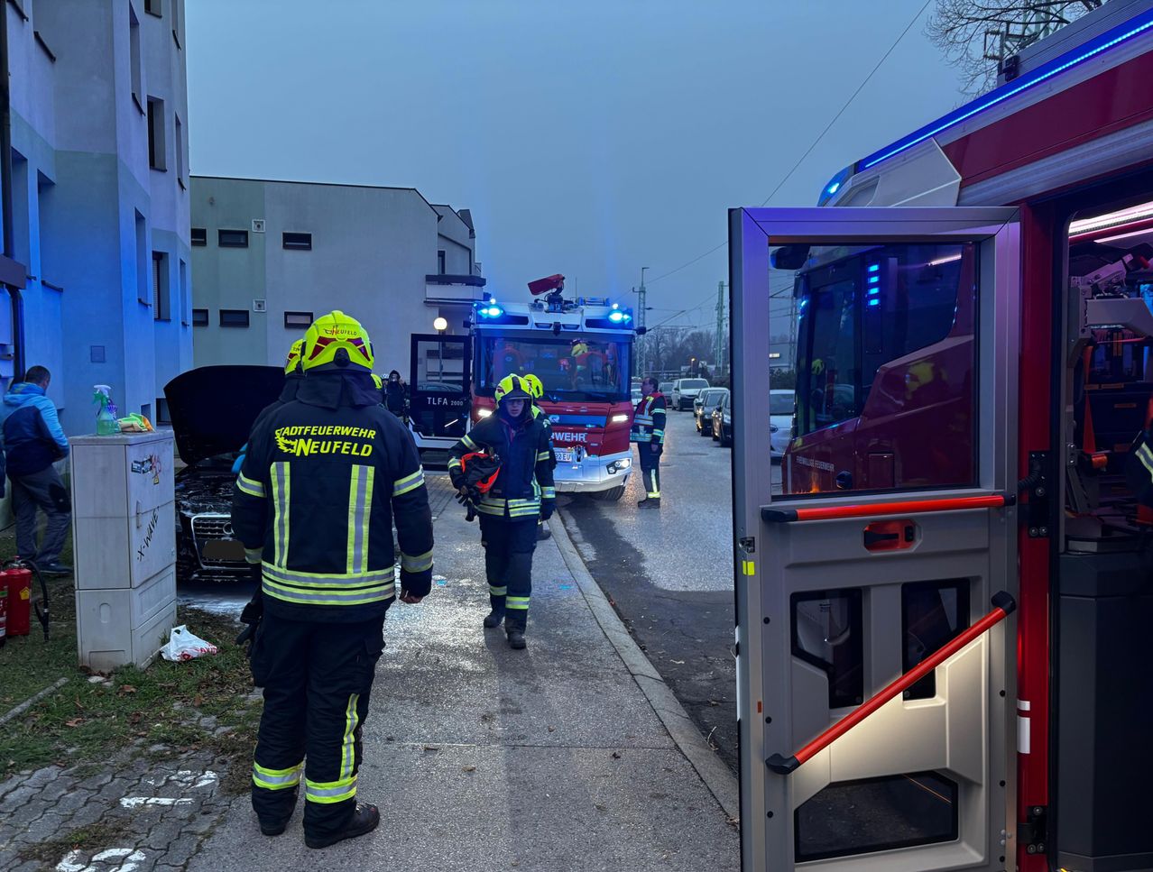 Feuerwehrleute aus Neufeld sind am Unfallort eines Autounfalls. Ein Auto ist beschädigt, und ein Feuerwehrauto ist in der Nähe geparkt.