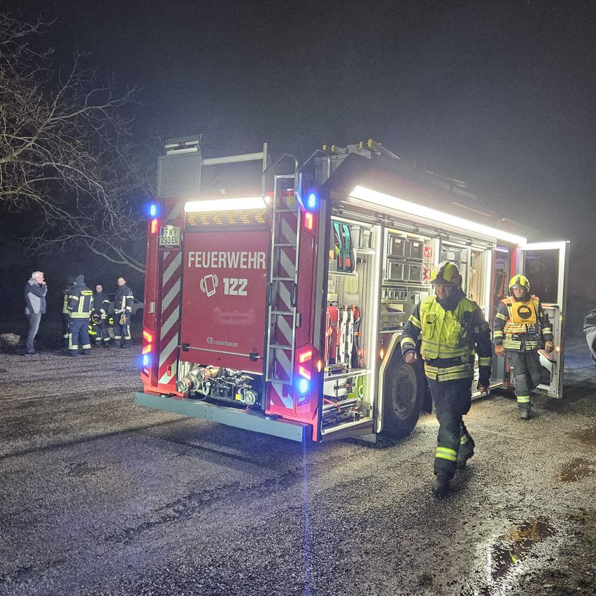 Feuerwehrleute stehen um einen Feuerwehrwagen mit der Nummer 122. Sie sind in voller Ausrüstung und scheinen sich auf einen Notfall vorzubereiten.