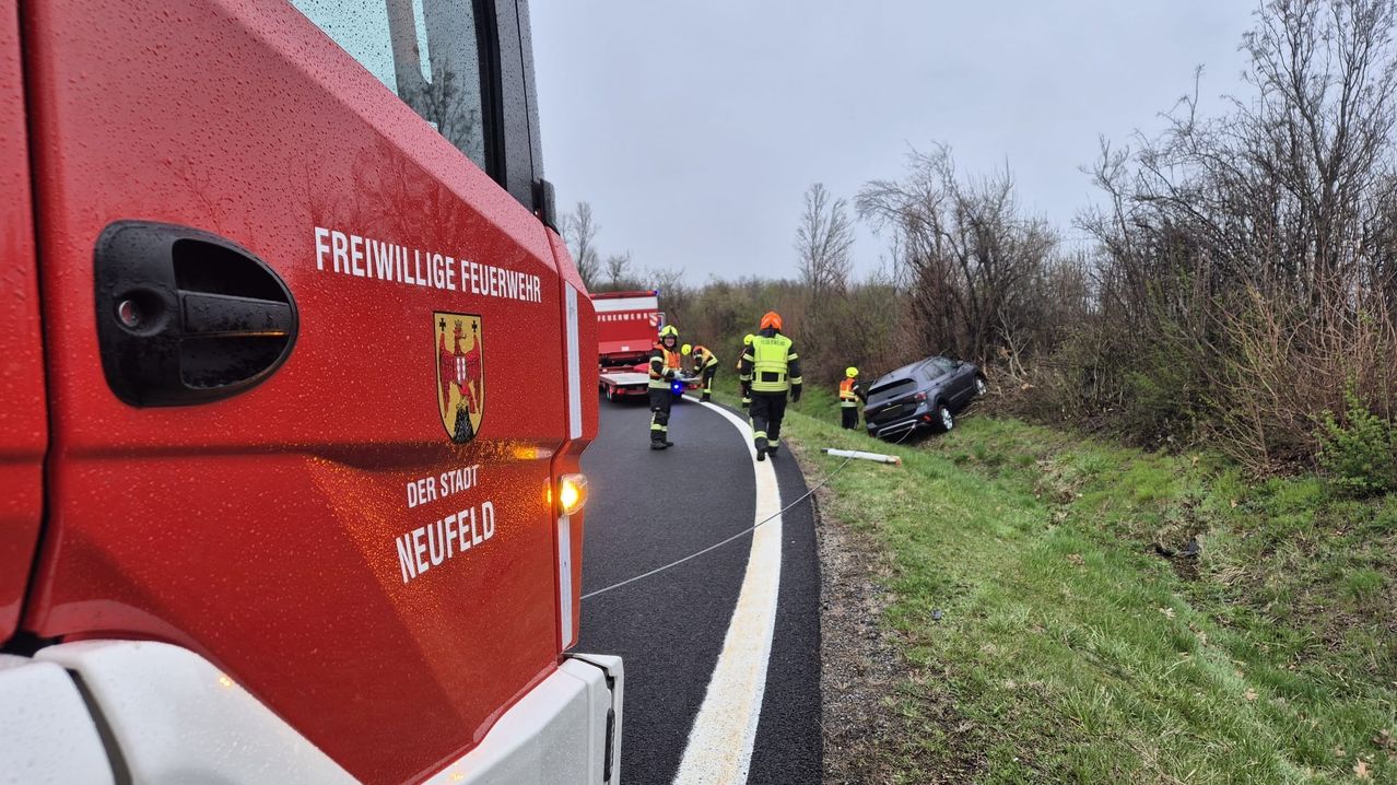 Einsatzkräfte sind am Unfallort, wo ein Fahrzeug von der Straße abgekommen ist. Ein Feuerwehrfahrzeug befindet sich in der Nähe.