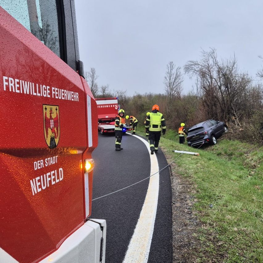 Einsatzkräfte sind am Unfallort, wo ein Fahrzeug von der Straße abgekommen ist. Ein Feuerwehrfahrzeug befindet sich in der Nähe.
