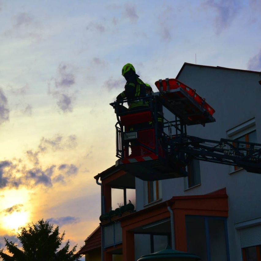 Ein Feuerwehrmann auf einer Leiterplattform reicht aus, um ein Gebäude zu erreichen, möglicherweise während einer Notlage.