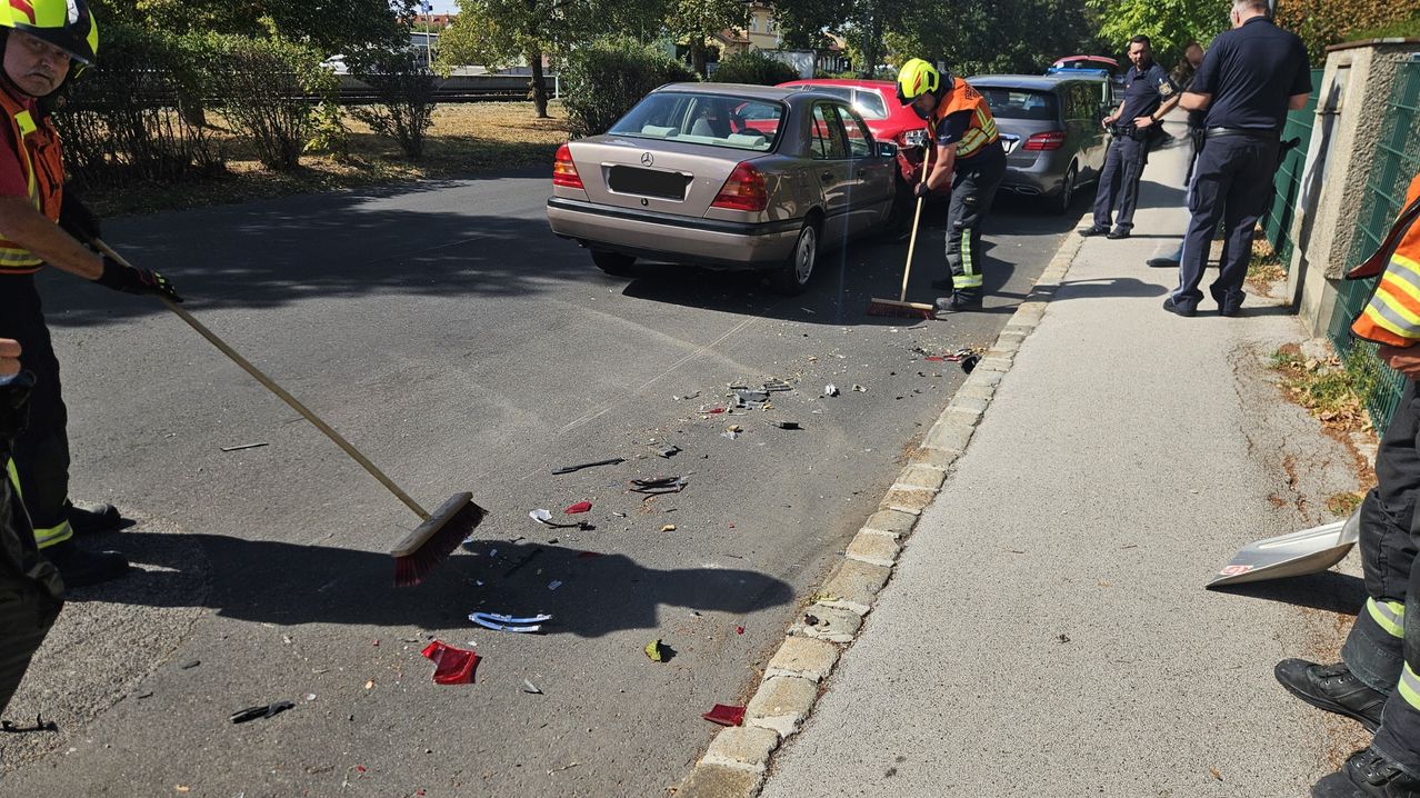 A firefighter is cleaning up debris from a car accident on the side of the road.