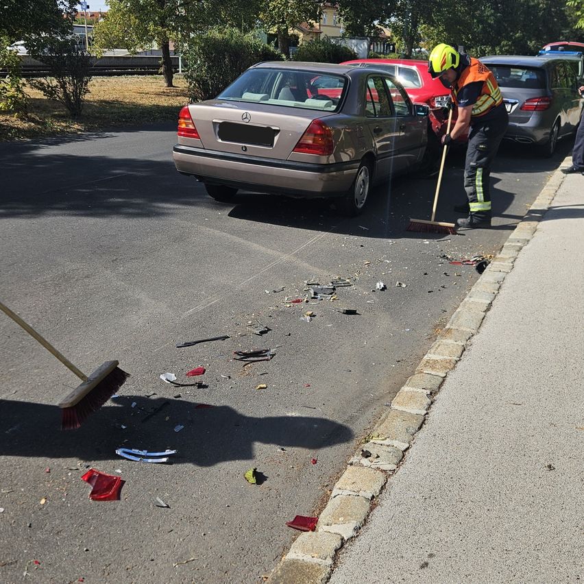Ein Feuerwehrmann räumt Trümmer von einem Autounfall am Straßenrand auf.