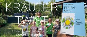 Eine Gruppe von Kindern und einer erwachsenen Frau in grünen Shirts posiert für ein Foto im Garten, wobei der Text 'Wilson's Garden & Solar Landwirtschaft' sichtbar ist.