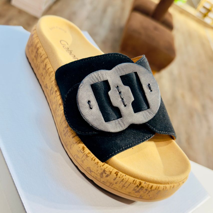 Ein gelber Sandale mit einem schwarzen Riemen und einer silbernen Schnalle wird auf einer weißen Oberfläche präsentiert. Der Sandale hat eine strukturierte Sohle und einen Markennamen 'Cebon', der auf dem oberen Teil geschrieben ist.