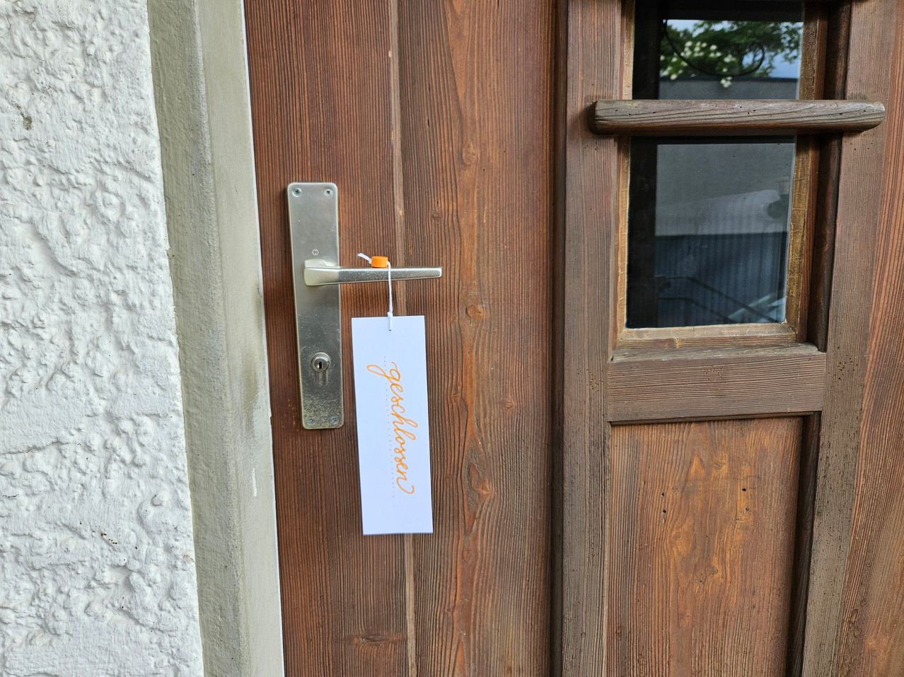 A wooden door with a silver handle and a tag reading 'peaceflower' attached to it. The door is closed, and a small orange piece of paper is attached to the handle.