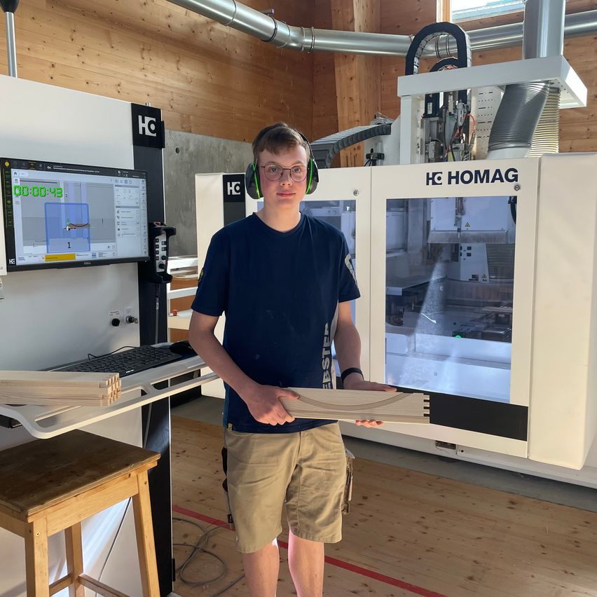 Bild enthält, Furniture, Table, Desk, Boy, Male, Person, Teen, Monitor, Headphones, Factory