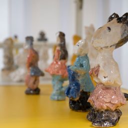 Nahaufnahme einer Gruppe von Keramikfiguren in verschiedenen Farben und Größen auf einem gelben Tisch.