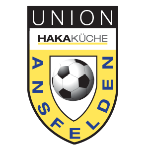 Das Logo des Union Hakakkuche Fußballvereins zeigt einen Schild mit dem Wort 'Union' oben, 'Hakakuche' darunter und einem Fußball im Zentrum. Der Schild ist gelb und blau.