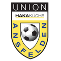 Das Logo des Union Hakakkuche Fußballvereins zeigt einen Schild mit dem Wort 'Union' oben, 'Hakakuche' darunter und einem Fußball im Zentrum. Der Schild ist gelb und blau.