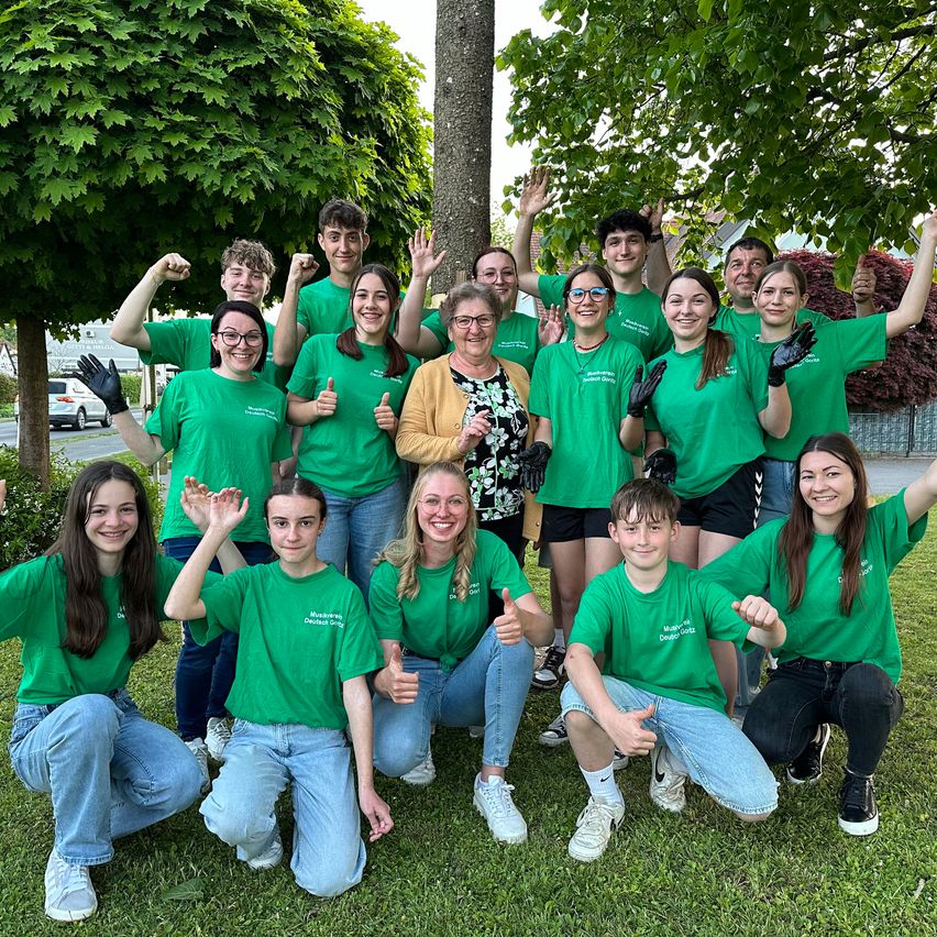 Eine Gruppe von Menschen in grünen Shirts posiert für ein Foto im Park.
