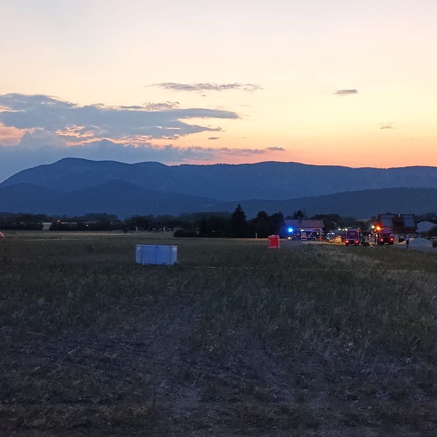 Ein Feld mit geparkten Rettungsfahrzeugen und einer Bergkette im Hintergrund während des Sonnenuntergangs.