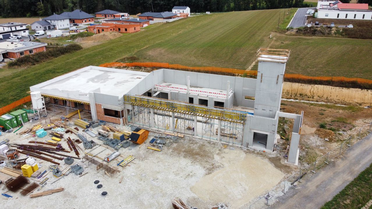 Aerial view of a construction site with a large building under construction and a field in the background.