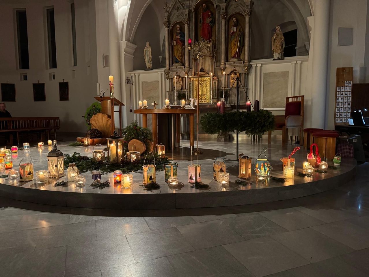 Eine Kapelle mit Altar, Statuen und einer kerzenbeleuchteten Einrichtung. Viele Laternen, Kerzen und Weihnachtsdekorationen schmücken den Boden.