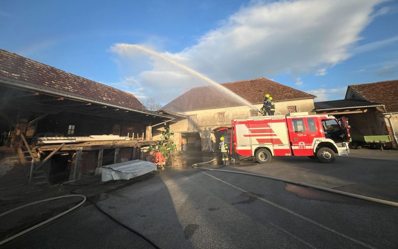 Feuerwehrleute benutzen einen Feuerwehrwagen, um Wasser auf ein Gebäude zu spühen, wahrscheinlich um ein Feuer zu löschen.